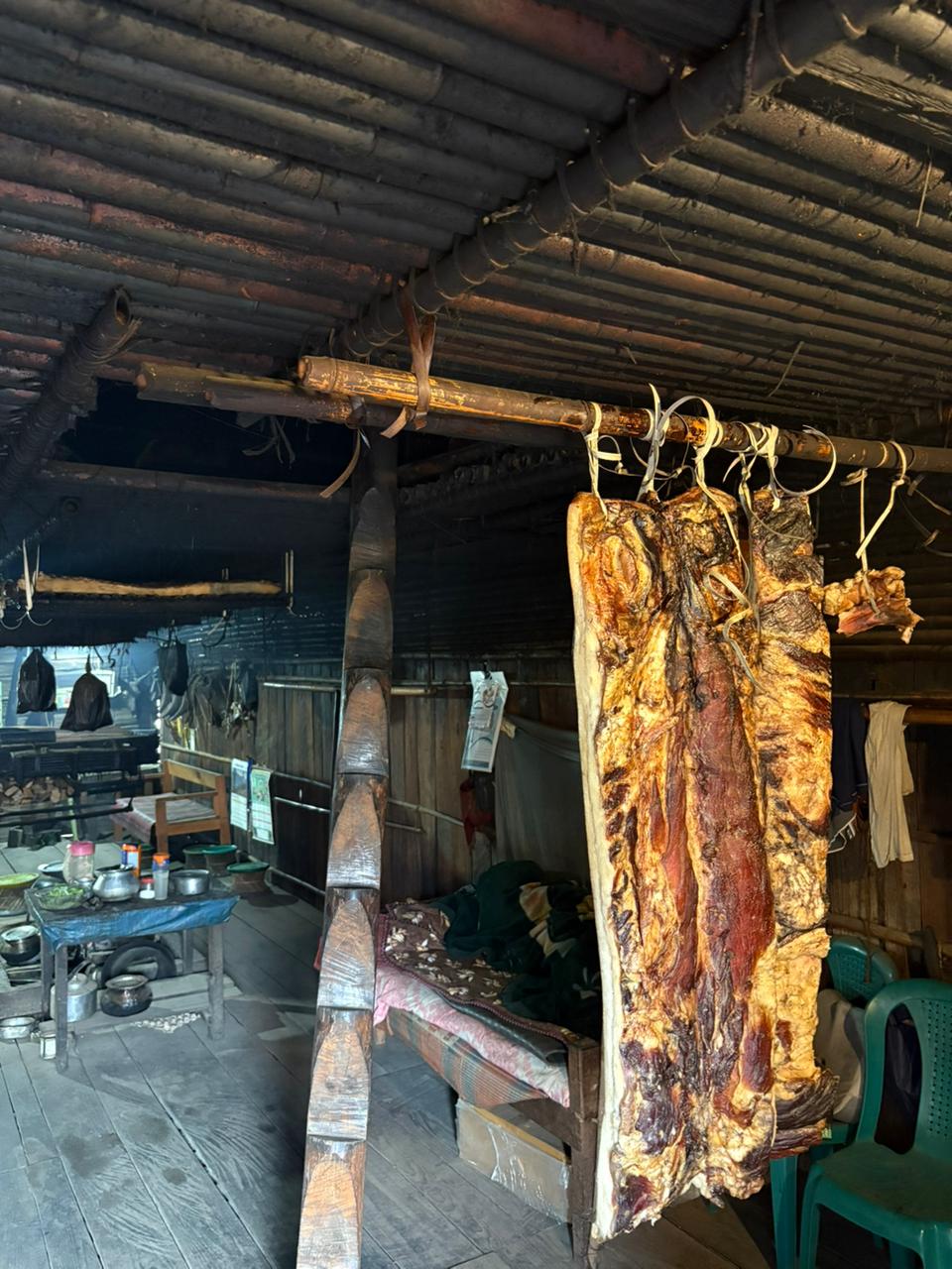 Smoked meat hanging above the hearth inside a traditional timber and bamboo house in Arunachal Pradesh