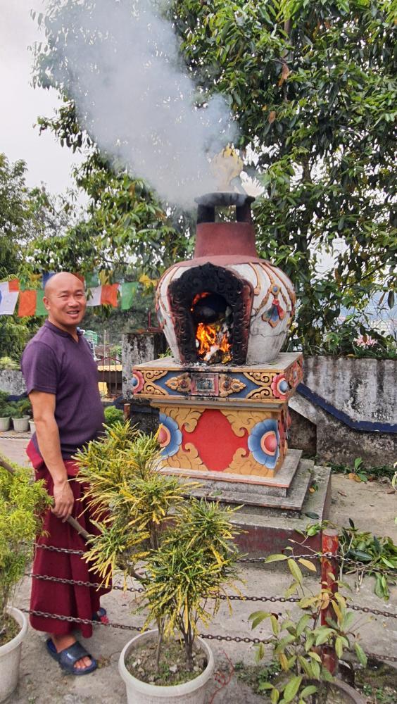 A Buddhist monk standing beside a ceremonial incense furnace in Arunachal Pradesh