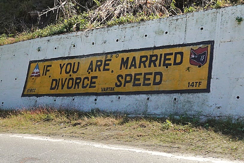 Painted road sign reading If You Are Married Divorce Speed on a hill road in Arunachal Pradesh