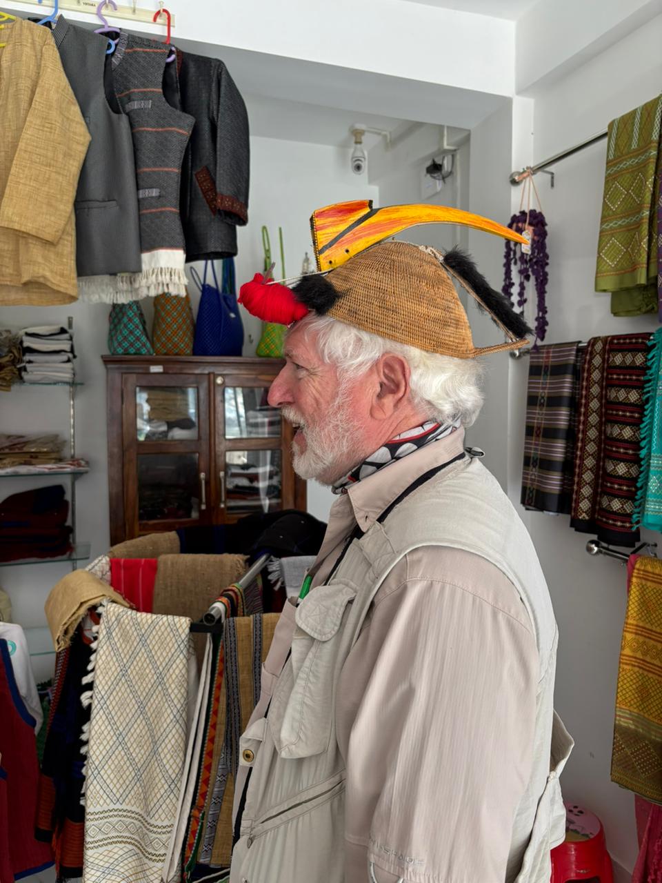 George Lowe trying on a traditional cane headdress in a handwoven textile shop in Northeast India