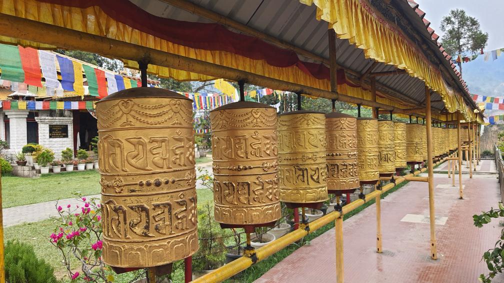 A long row of golden Buddhist prayer wheels at a monastery in Arunachal Pradesh