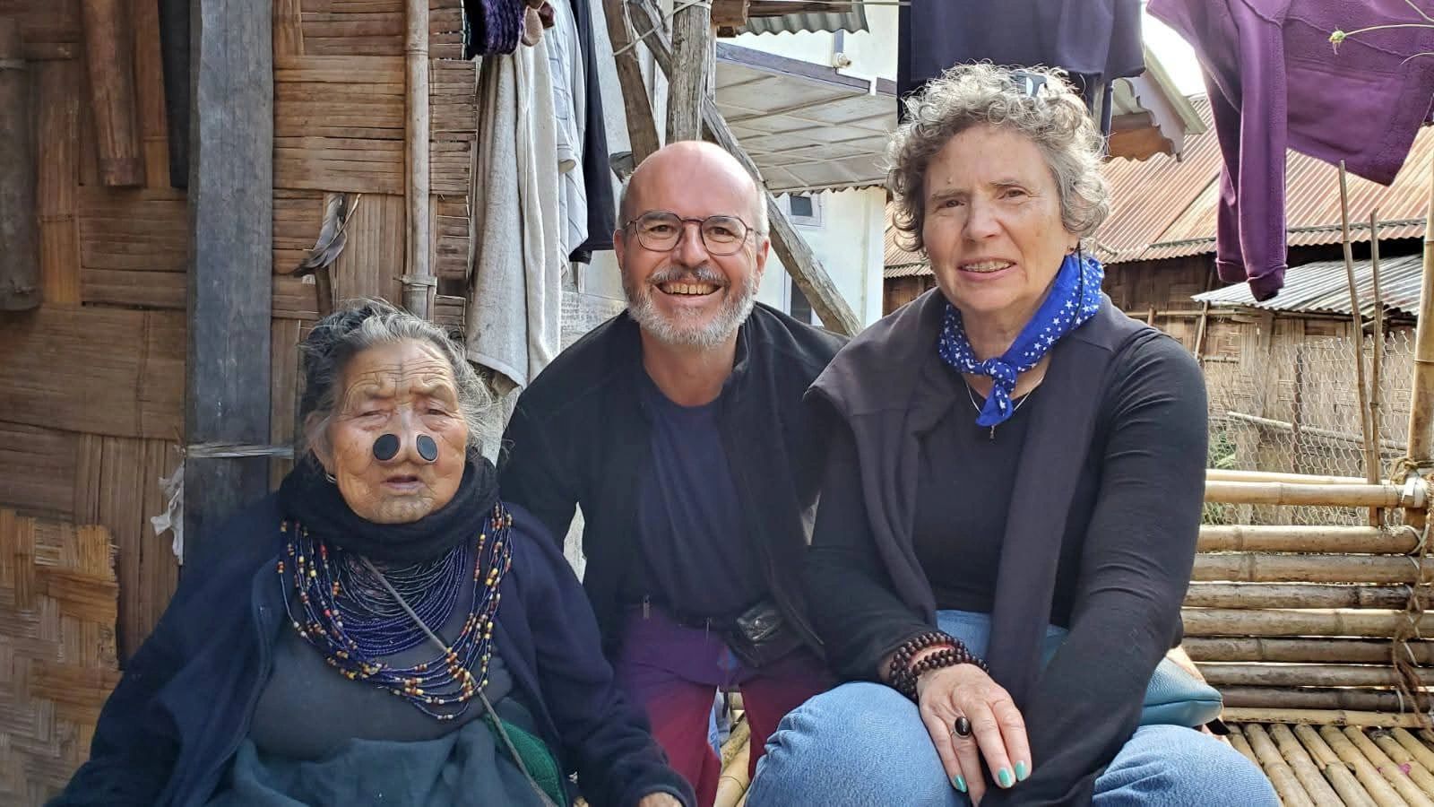 Apatani tribal elder with travellers outside a bamboo home, Arunachal Pradesh