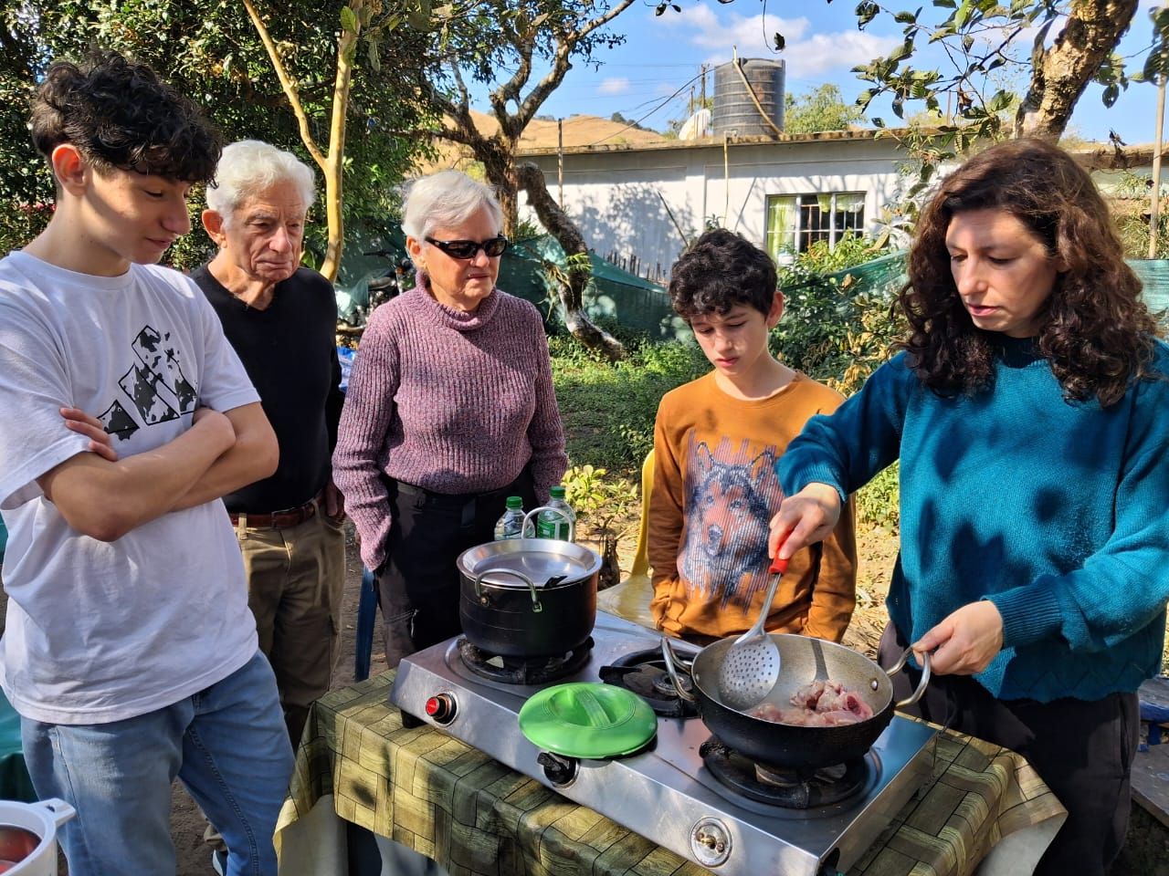 Family learning a traditional Khasi cooking ritual outdoors